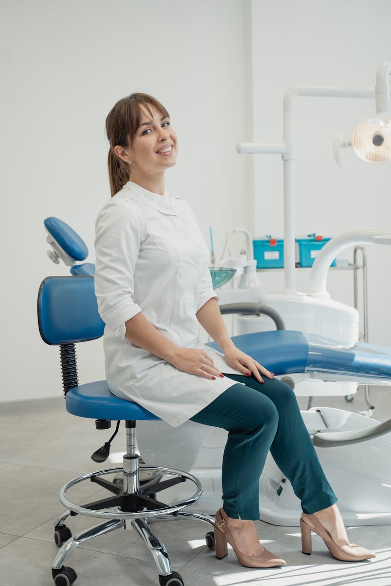Professional female dentist sitting in a modern, well-equipped dental office.
